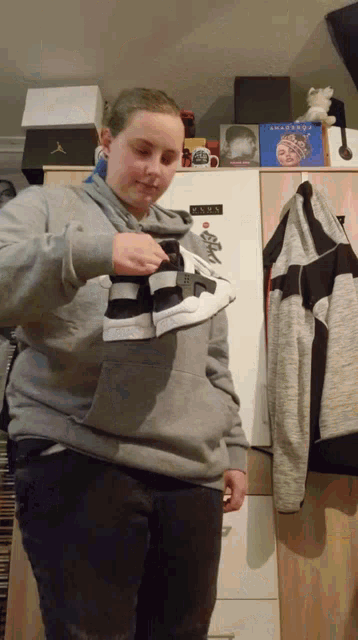 a person holding a pair of shoes in front of a fridge with a sticker on it that says ' casa ' on it