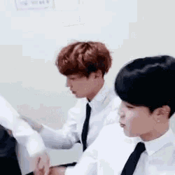 two men in suits and ties are sitting next to each other .