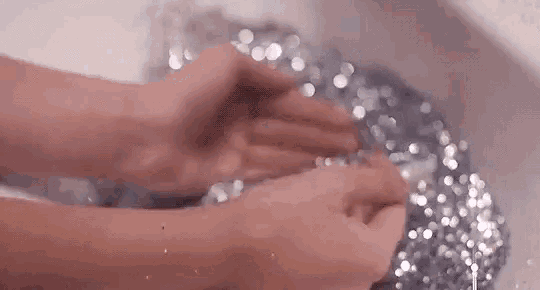 a person is washing their hands in a sink filled with water .