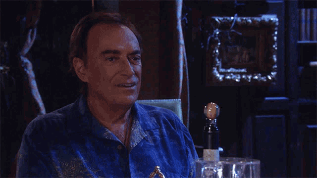 a man in a blue shirt is sitting in a dark room