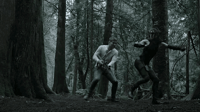 a man and a woman are fighting in a forest
