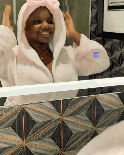 a woman in a bathrobe looks at herself in a mirror