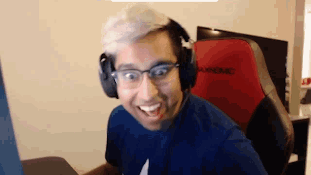 a man wearing headphones and glasses is sitting in a chair that says aunomc on the back