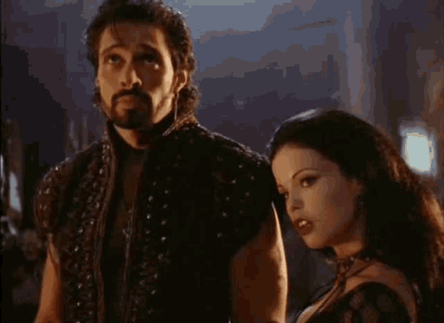 a man and a woman are standing next to each other in a dark room .