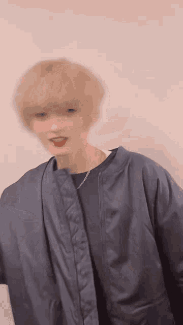 a blurry picture of a person wearing a blue jacket and a black shirt .