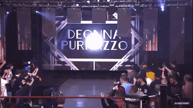 a crowd of people watching a wrestling match with a large screen behind them that says d puzo