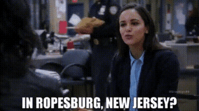 a woman in a suit and tie is talking to a police officer in ropesburg , new jersey .