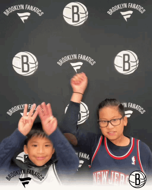 two young boys pose in front of a brooklyn fanatics banner