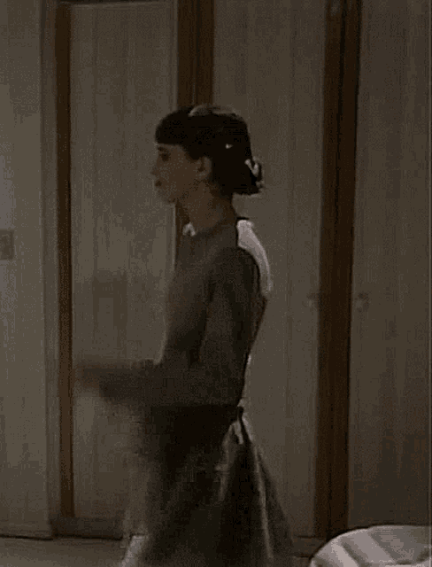 a woman is standing in front of a door covering her face with her hands
