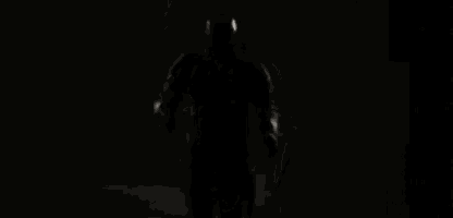 a man in a mask is holding a gun in his hand in the dark .