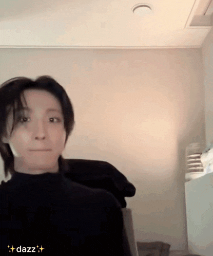 a man in a black turtleneck sweater is making a funny face in a room with the word dazz in the corner