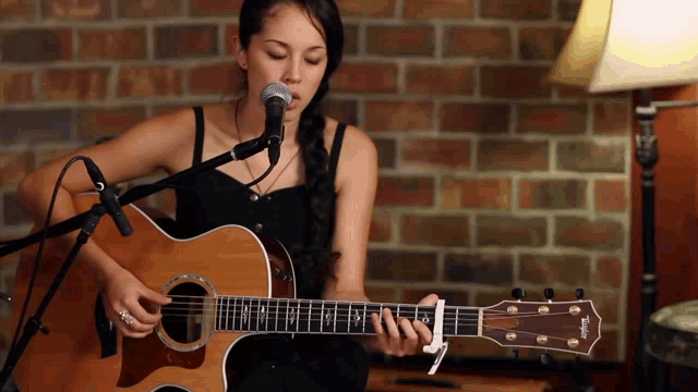 a woman singing into a taylor guitar
