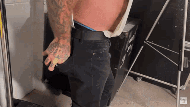 a man with a tattoo on his arm is standing in front of a box that says ' a ' on it