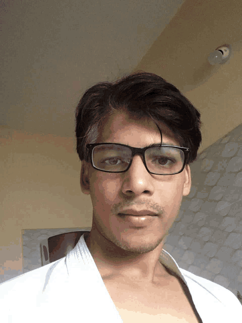 a man wearing glasses and a white shirt is taking a selfie
