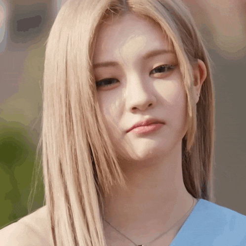 a woman with blonde hair is wearing a blue top and necklace