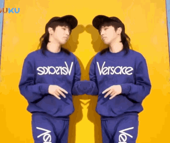 a man wearing a blue versace sweatshirt is standing next to another man