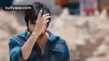 a man is covering his face with his hand and looking at the camera .