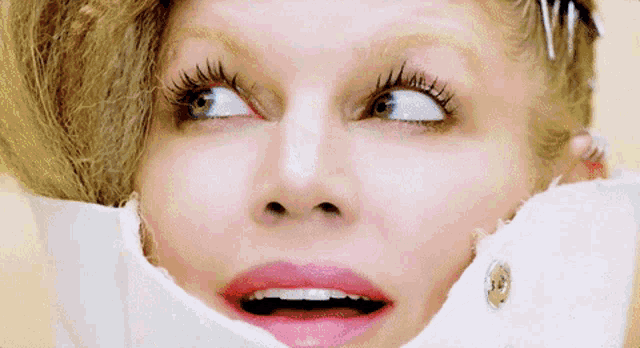 a close up of a woman 's face with a white shirt covering her mouth