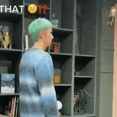 a man with green hair is standing in front of a bookshelf and a sign that says that 17