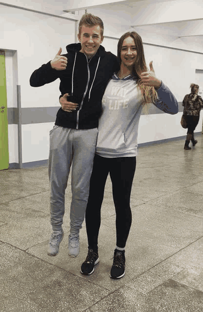 a man and a woman are posing for a photo and the woman is wearing a sweatshirt that says way of life