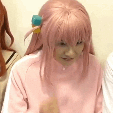 a woman wearing a pink wig and a pink sweater is sitting in a room .