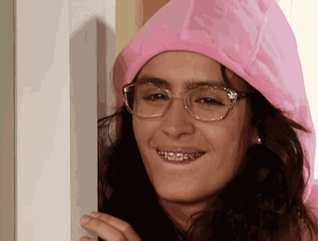 a woman wearing braces and a pink hoodie is smiling