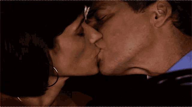a man and a woman are kissing in the dark
