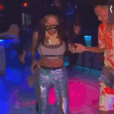 a woman in a crop top and sequined pants is standing next to a man in red shorts