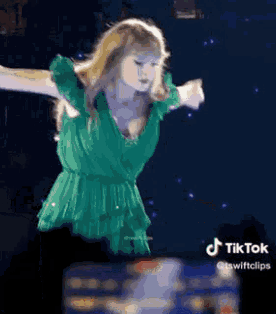 taylor swift is wearing a green dress and dancing on a stage .