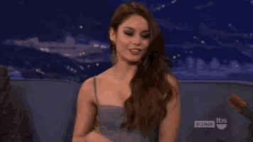 a woman is sitting on a couch with her arms outstretched and laughing .