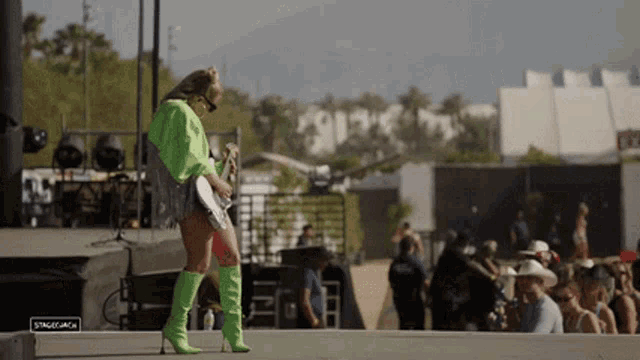 a woman in green boots is playing a guitar on stage .
