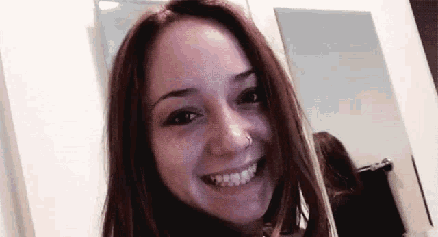 a woman is smiling in front of a mirror in a room .
