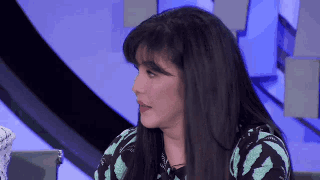 a woman with long dark hair is wearing a black and green shirt