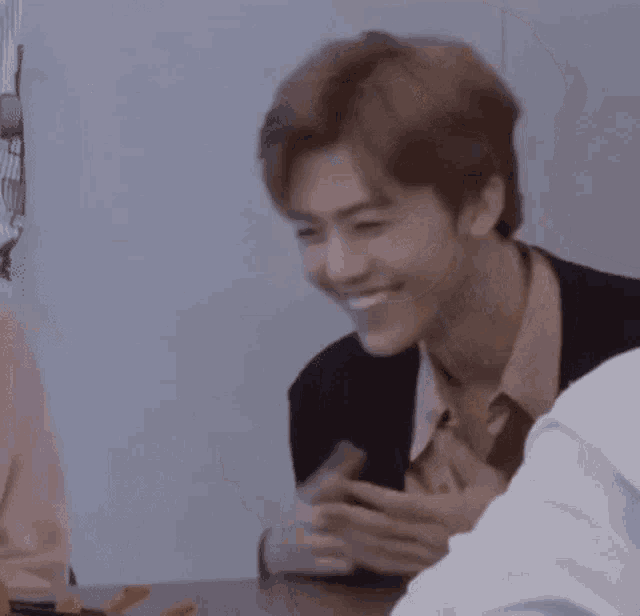 a man is sitting at a table with another man and smiling .