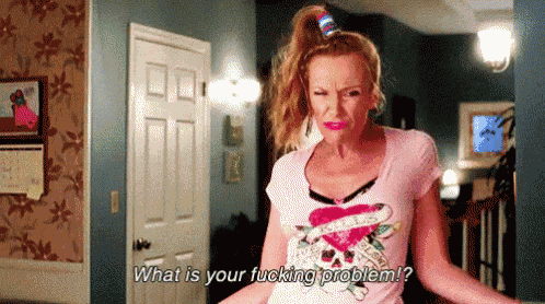 a woman wearing a pink shirt with a heart on it is asking what is your fucking problem .