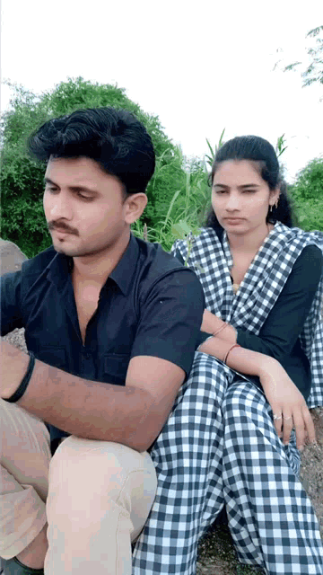 a man and a woman are sitting next to each other in a field