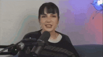 a woman is smiling in front of a microphone while sitting on a couch .