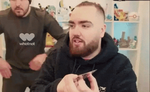 a man with a beard is holding a card in his hand while another man looks on .
