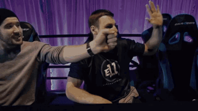 a man wearing a shirt that says e11 is giving a high five to another man