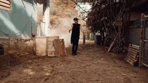 a man is walking down a dirt road in front of a building .