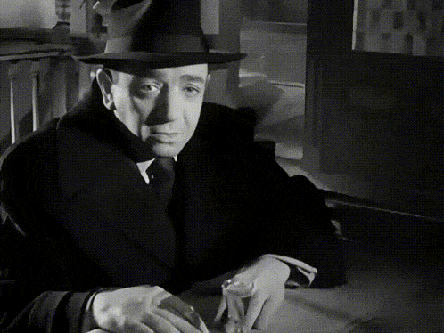a black and white photo of a man wearing a hat and coat