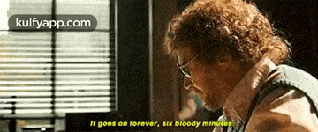 a man with glasses is sitting in front of a window and says it goes on forever six bloody minutes .