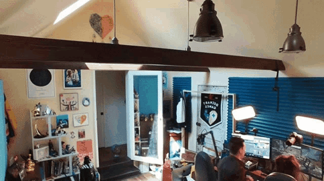 a man sits at a desk in a room with a league logo on the wall