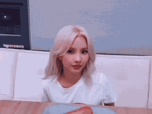 a woman with blonde hair is sitting at a table with a plate of food in front of her .