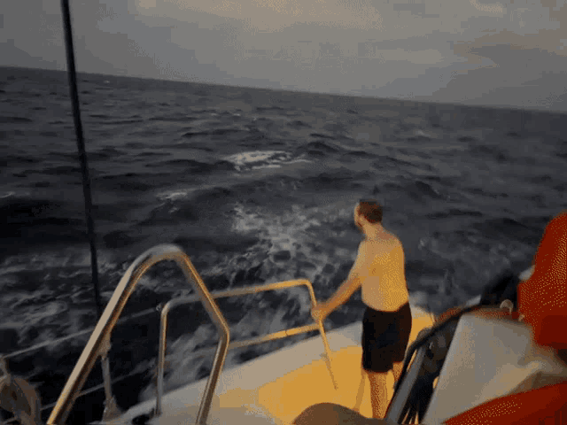 a shirtless man is standing on a boat in the middle of the ocean