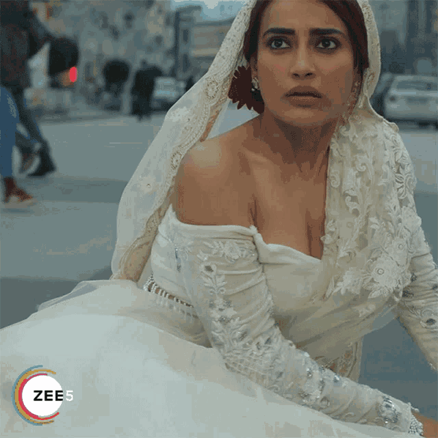a woman in a white dress with a veil on her head has the word zee5 on the bottom