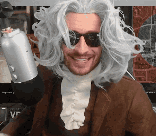 a man wearing a wig and sunglasses is smiling in front of a microphone that says operation vf