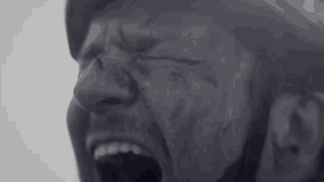 a black and white photo of a man screaming with his mouth wide open .
