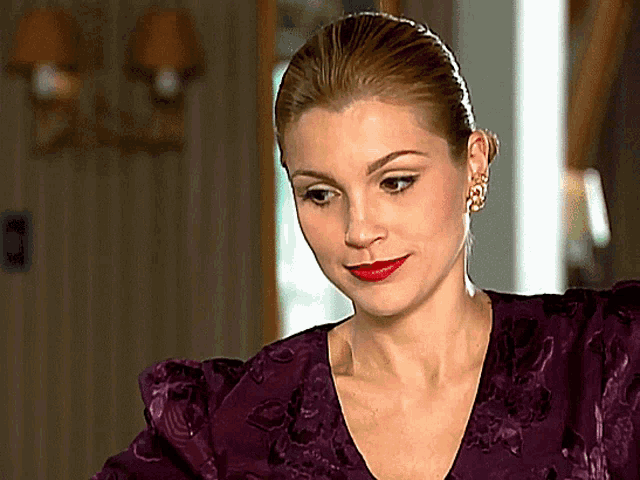 a woman in a purple dress with red lipstick and earrings