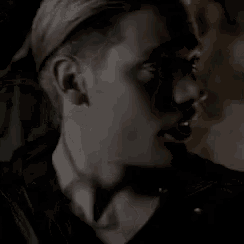 a close up of a man 's face in a dark room with a shadow on his face .